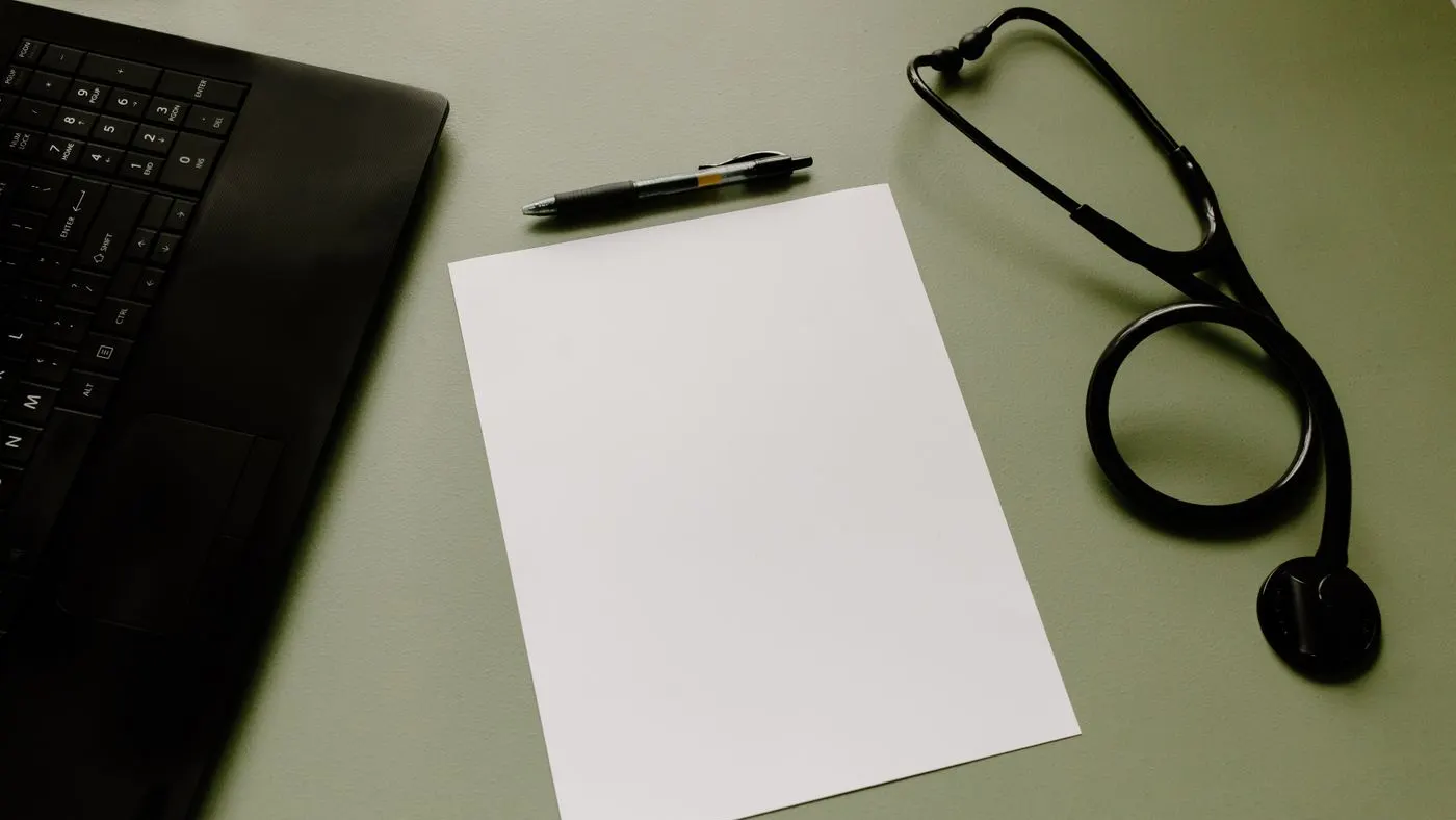 Computador portátil, una hoja blanca, un bolígrafo y un estetoscopio negro sobre un escritorio verde grisáceo: los datos que se reúnen para calcular el riesgo cardiovascular